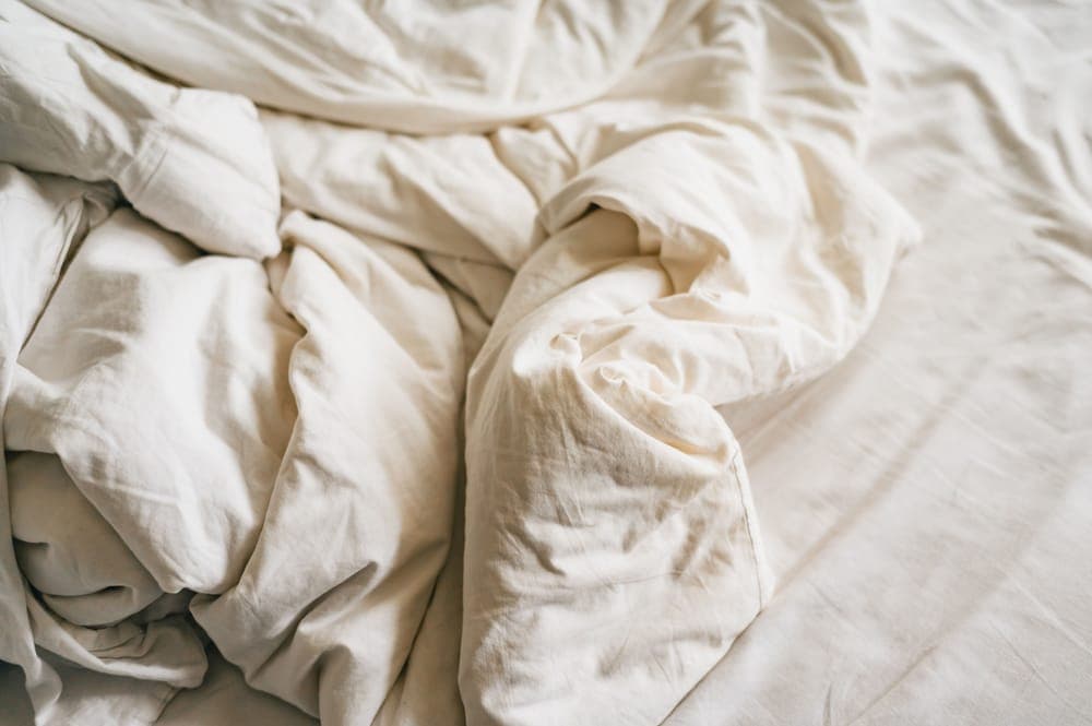 Close-up of rumpled cream bed linen