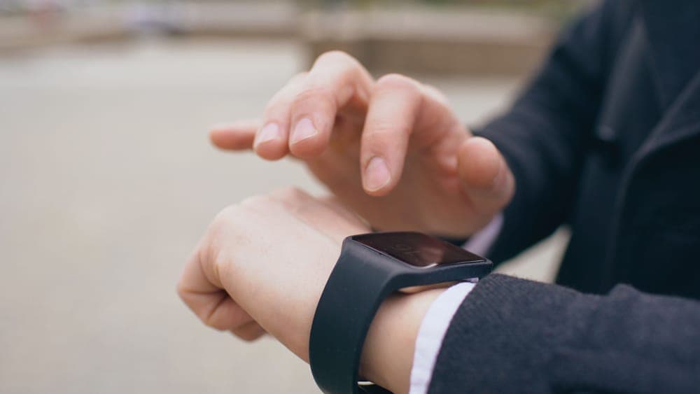 A person tapping a smartwatch with a blank screen on their wrist